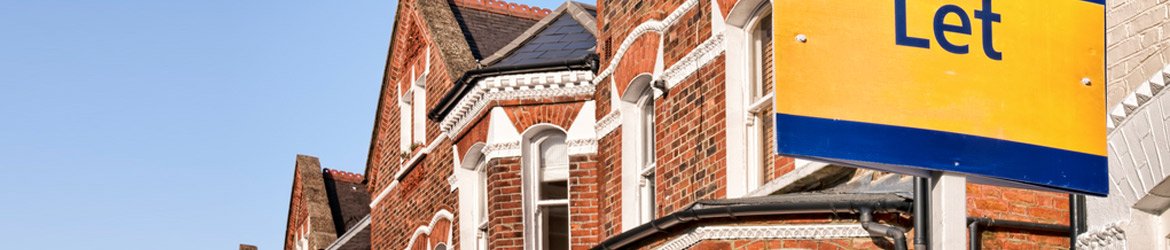 A row of red-brick Victorian terraced houses under a clear sky